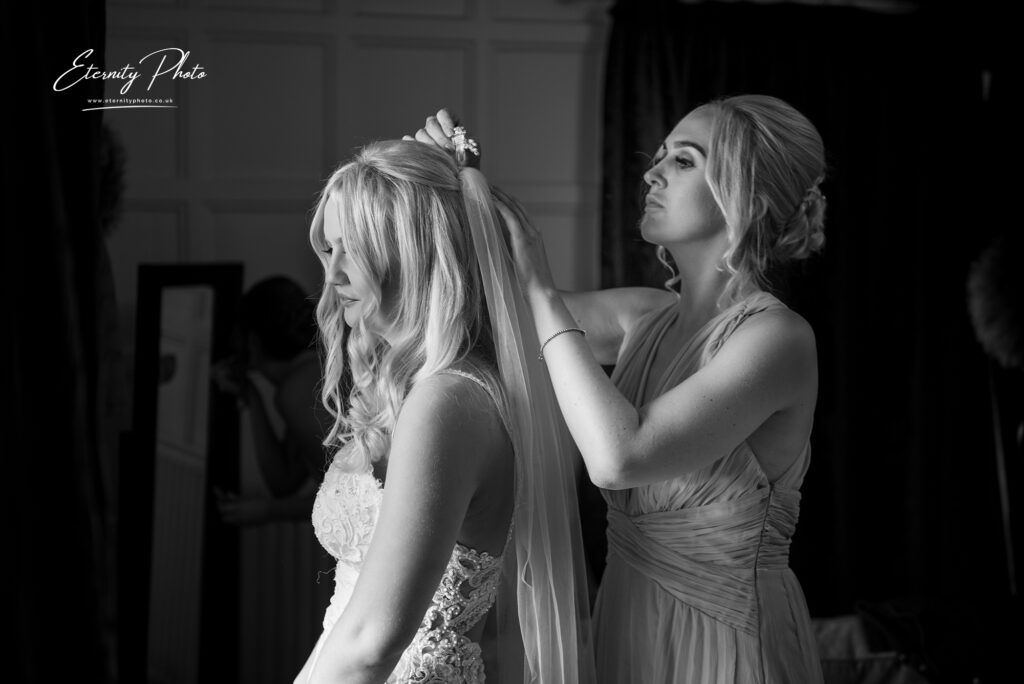 A bridesmaid adjusting the bridal veil of the bride before the wedding ceremony.