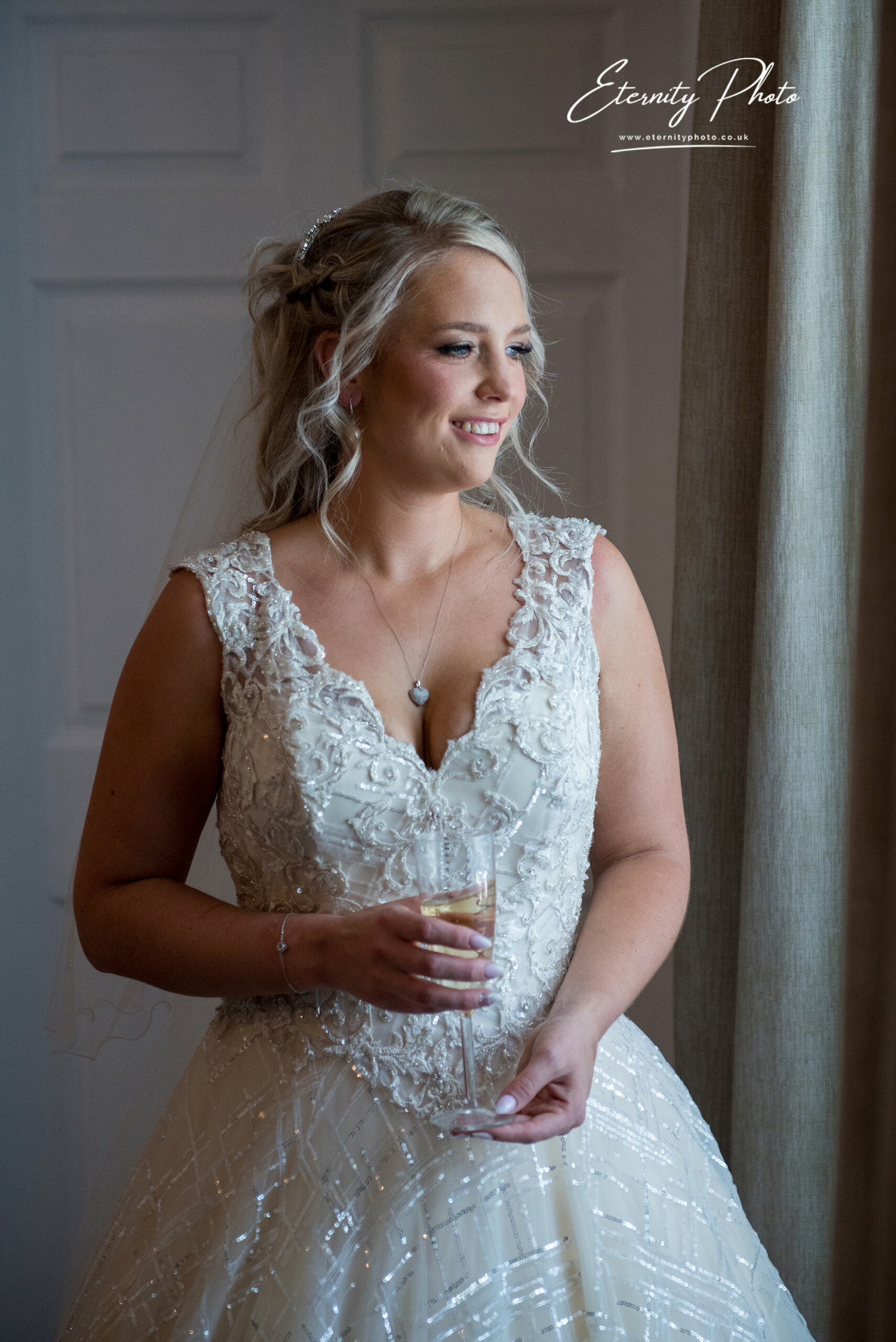 Bride in white dress smiling with champagne glass.