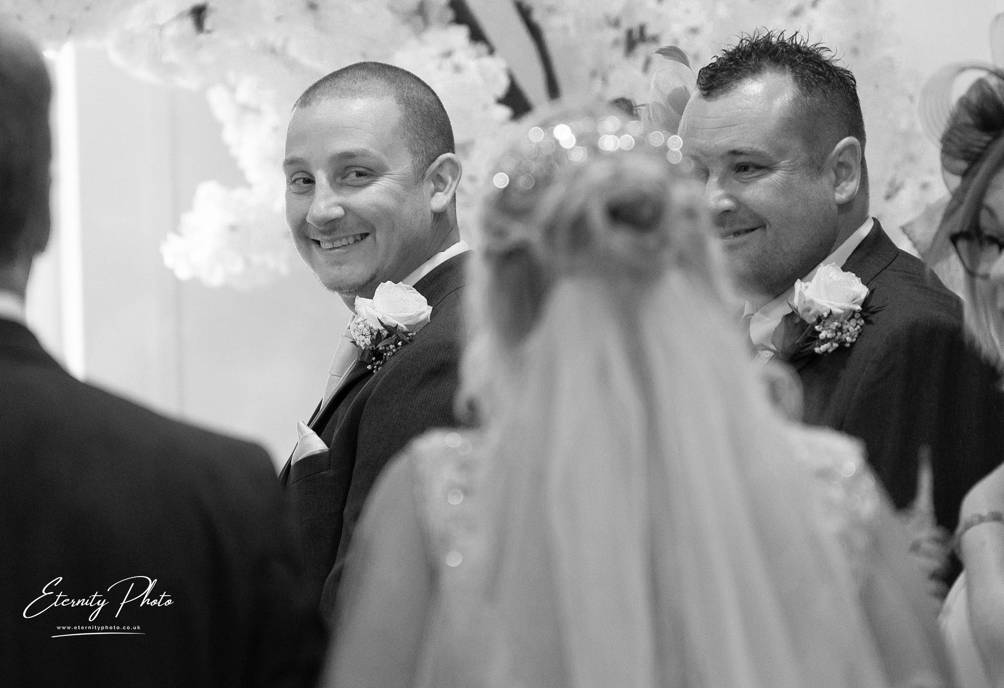 Smiling grooms at wedding ceremony in black and white.