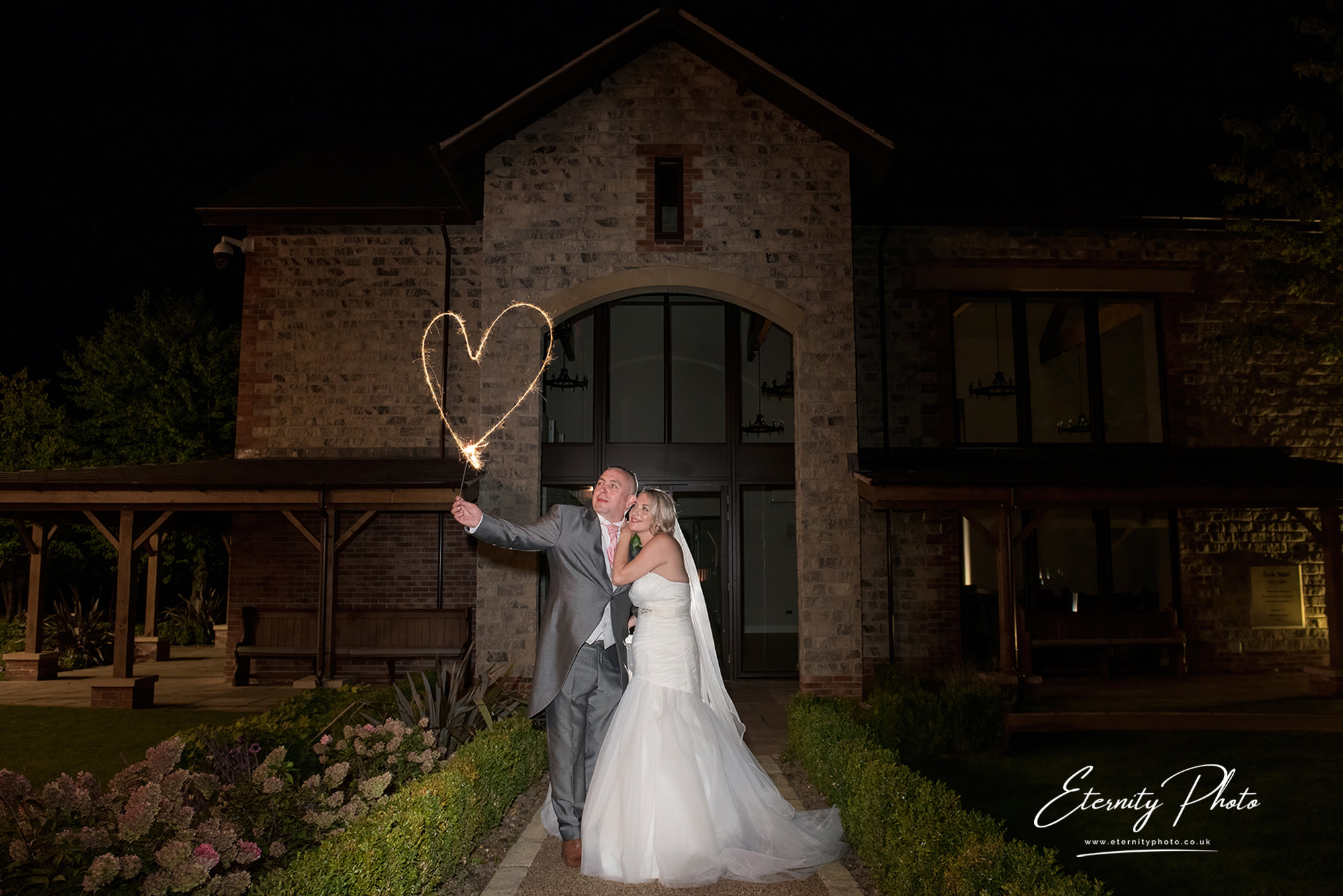 Couple with sparkler heart at night wedding.