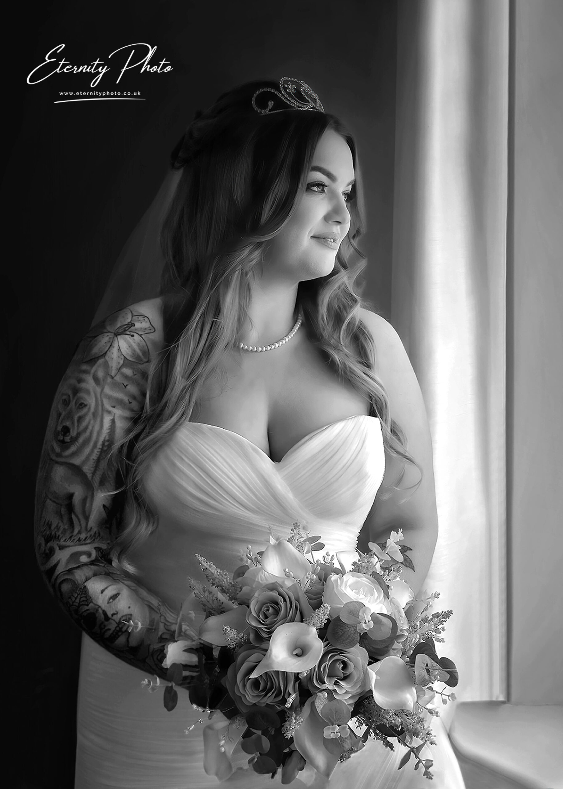 Tattooed bride in white gown holding bouquet, black and white.