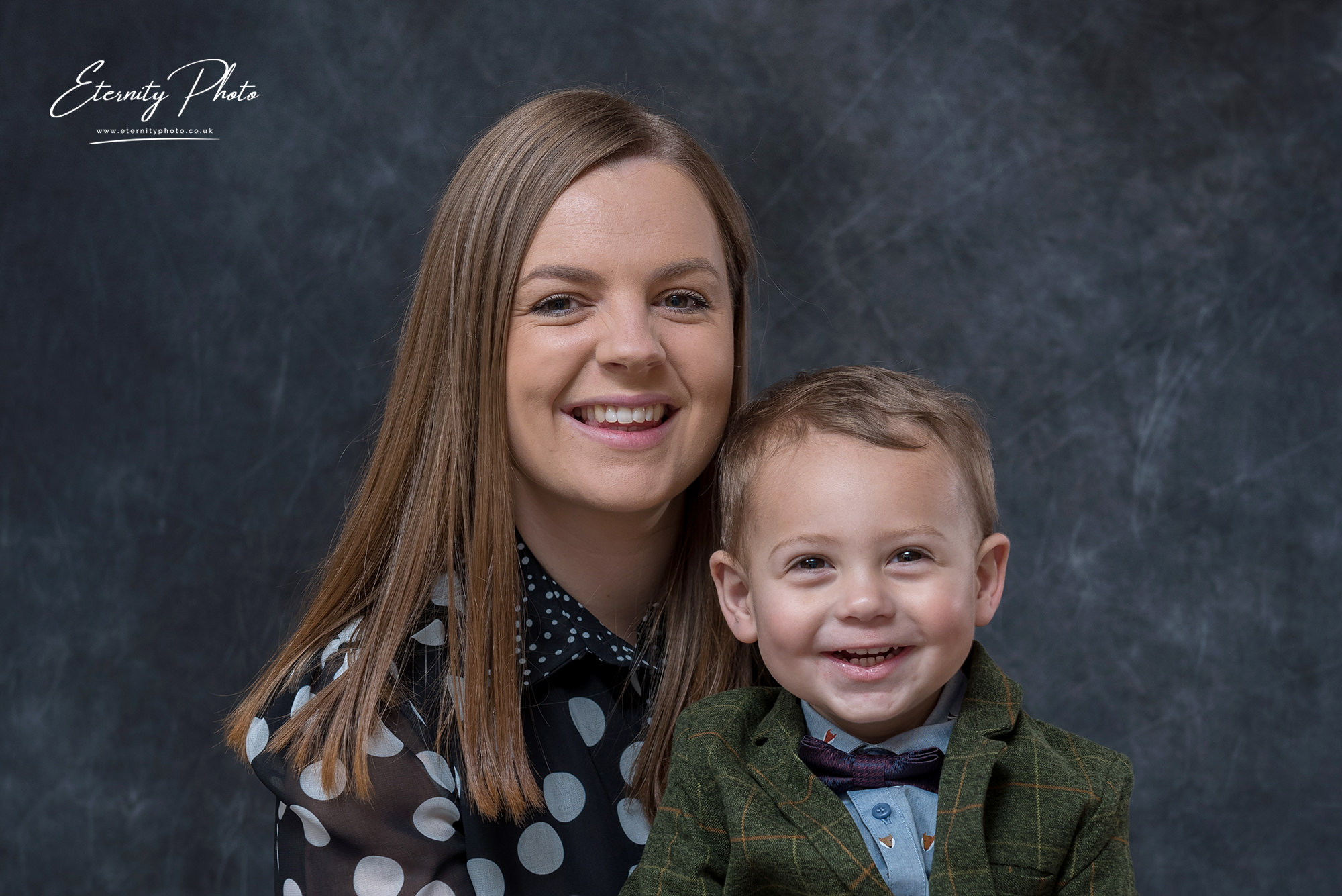Woman and toddler smiling, studio portrait session.