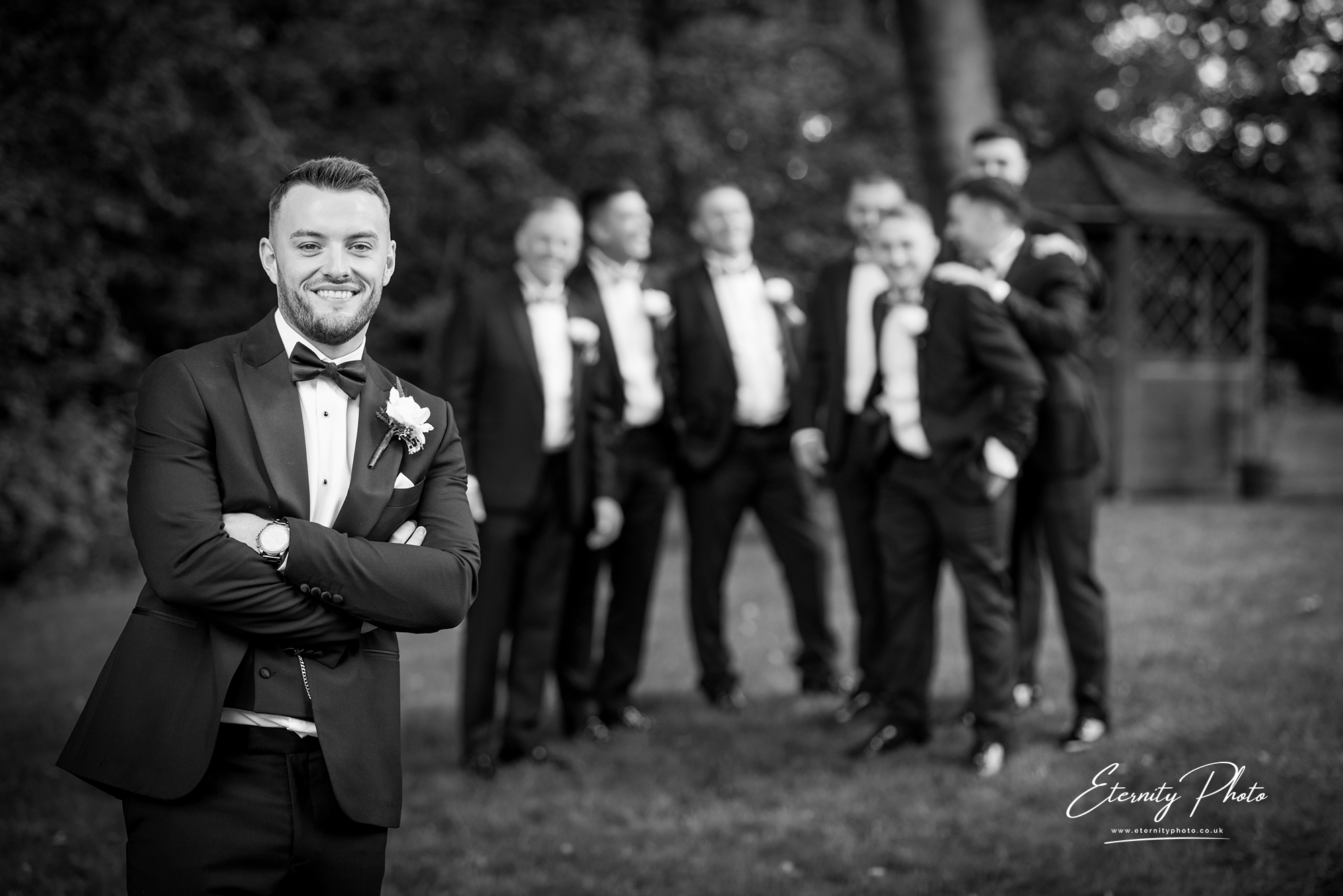 Groom with groomsmen in formal black-tie attire.