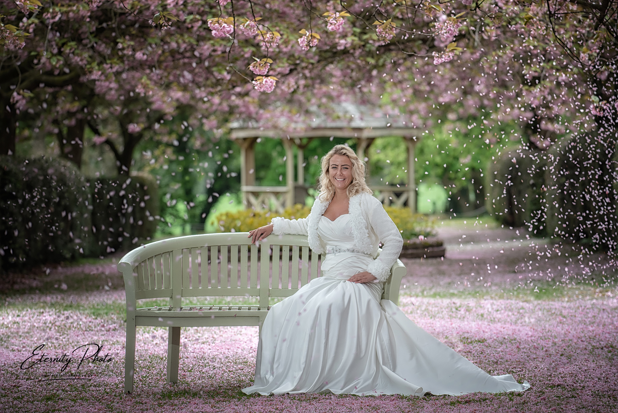 Woman in wedding dress under blossoming cherry trees.