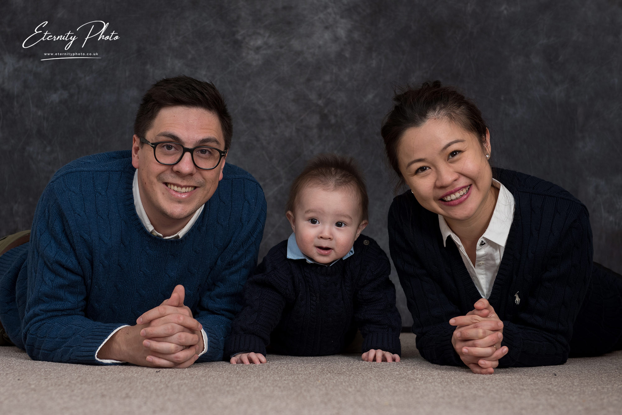 Family portrait with smiling parents and baby.