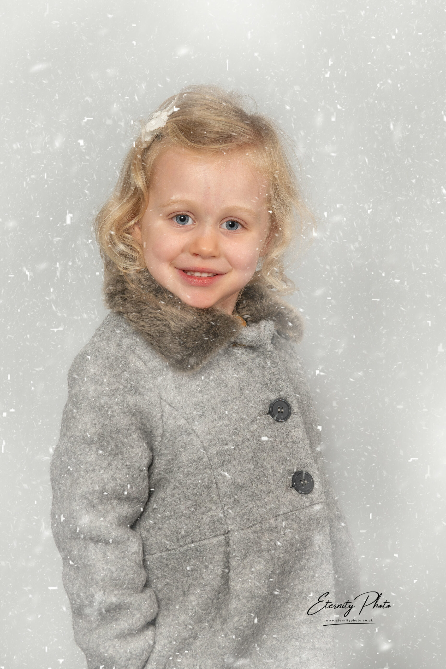 Child in grey coat, snowfall background.