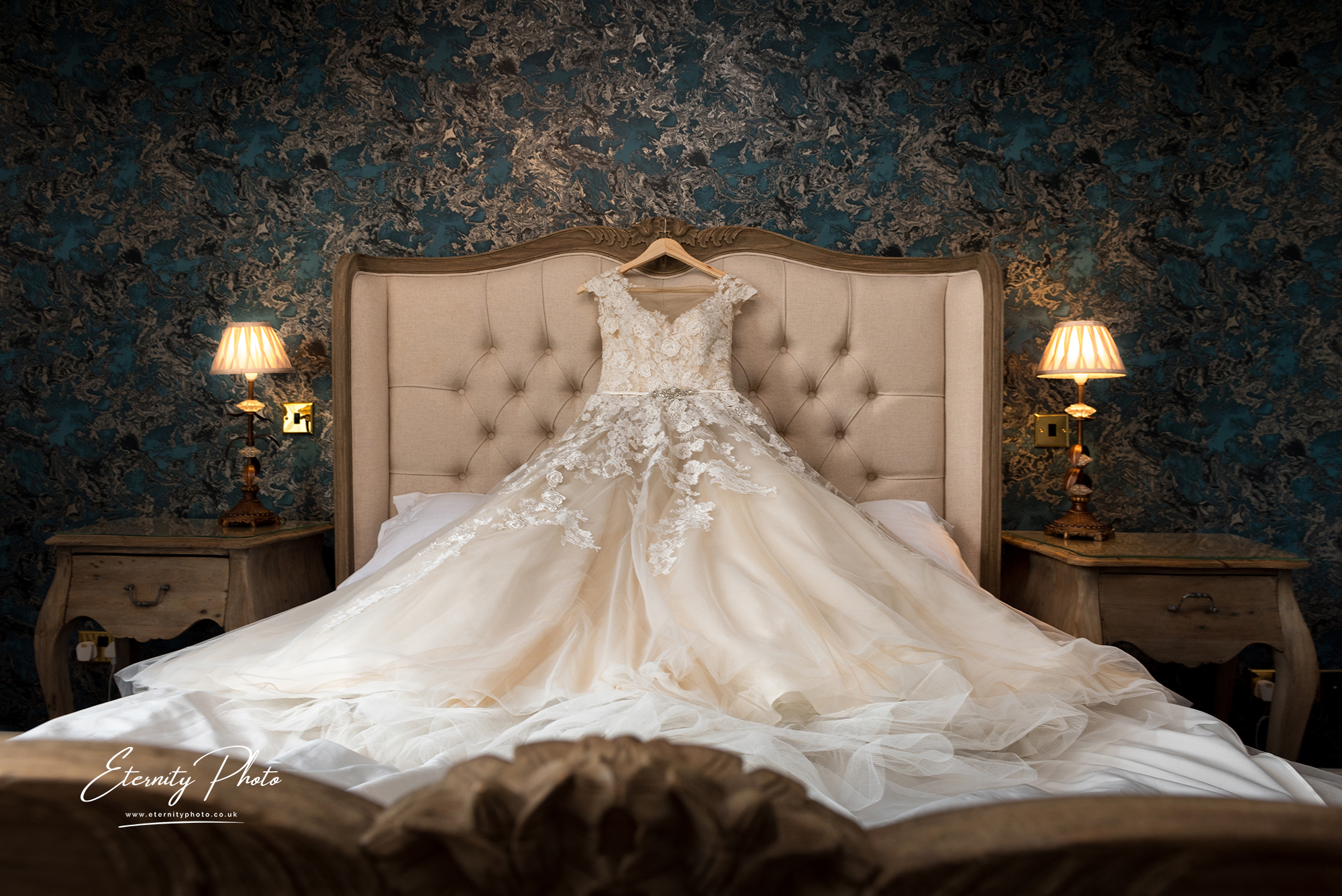 Elegant wedding dress on bed with vintage decor.